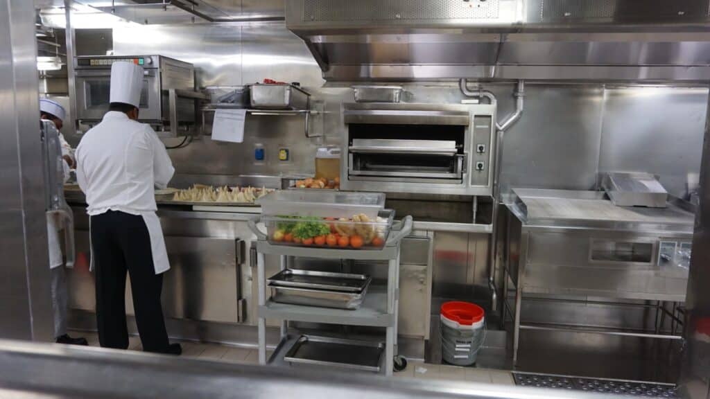 A chef prepares food inside the kitchen on a cruise ship