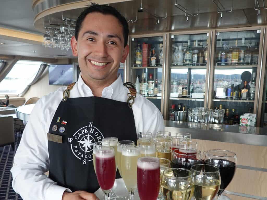 Cruise ship waiter with a tray of alcoholic drinks and smiling at the camera